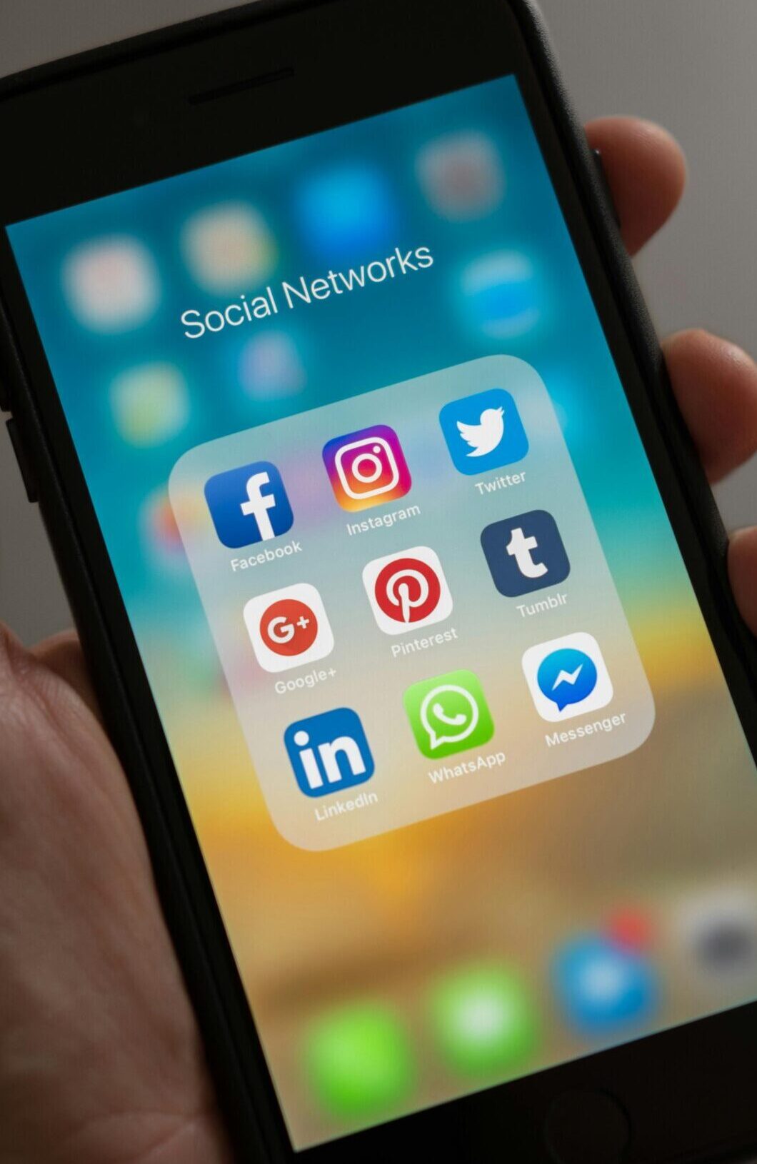A smartphone displaying various social media icons held in a hand, showcasing modern communication apps.