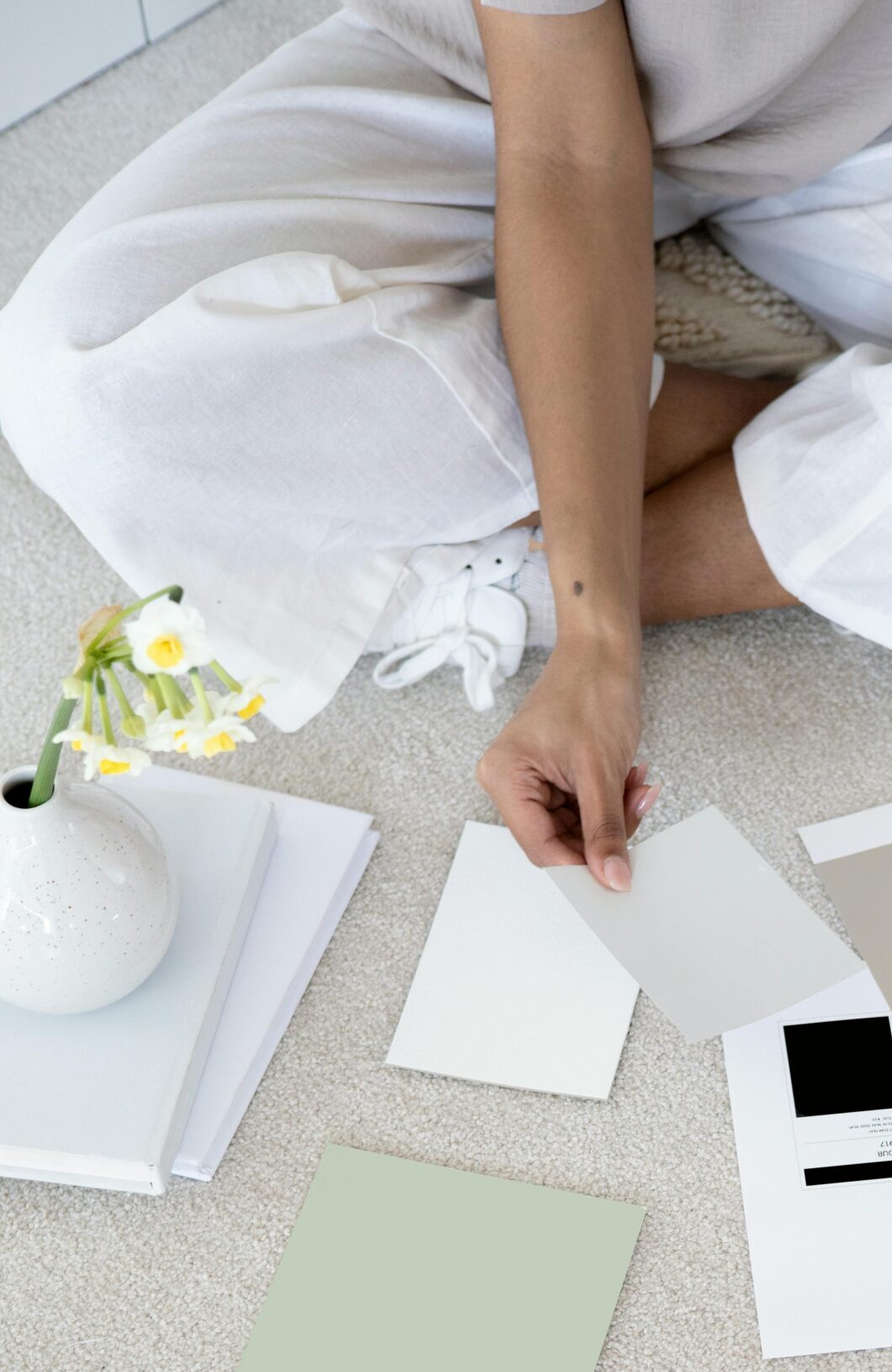 Designer sits on carpet with color palettes and samples, planning creative project.