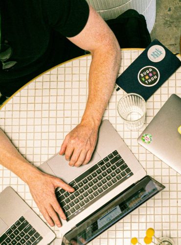 Top view of a team collaborating with laptops, phones, and notes in a modern office.