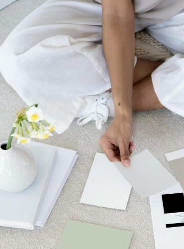 Designer sits on carpet with color palettes and samples, planning creative project.